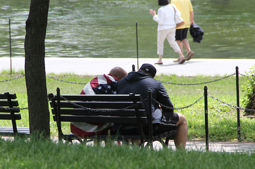 Two OAS attendees comfort each other by the reflecting pool, in a photo by Carl Woodward