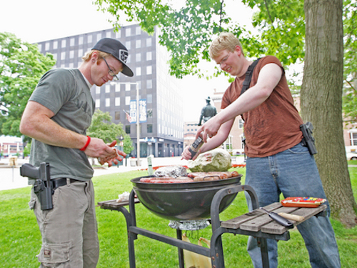 Kalamazoo residents wear their guns next to a grill at the Open Carry Picnic.